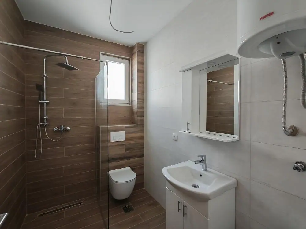 Kupatilo sa tuš-zonom, konzolnom WC šoljom i bojlerom — Ledine, Višegradska — dvosoban stan u novogradnji, 45,3 m²